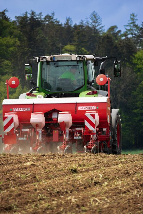 Traktor mit Einzelkornsähmaschine bearbeitet ein Feld.