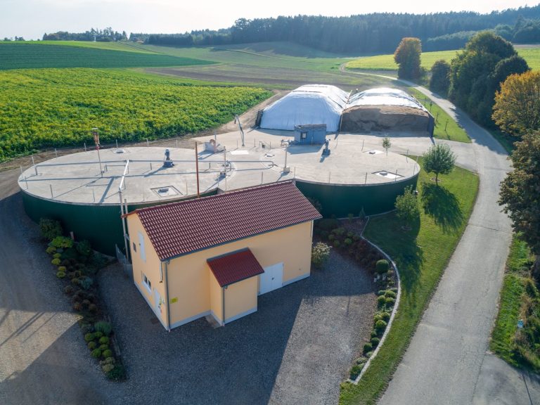 Biogasanlage mit zwei Gruben, einem kleinen gelben Gebäude und zwei Silos