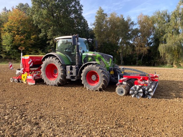 Grüner Traktor mit roter Saatmaschine auf einem Frontpacker